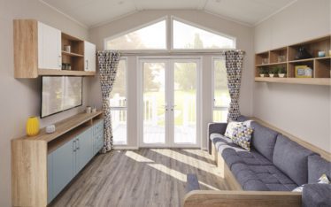 White french doors in the back of a living room leading out to a sunlit patio.