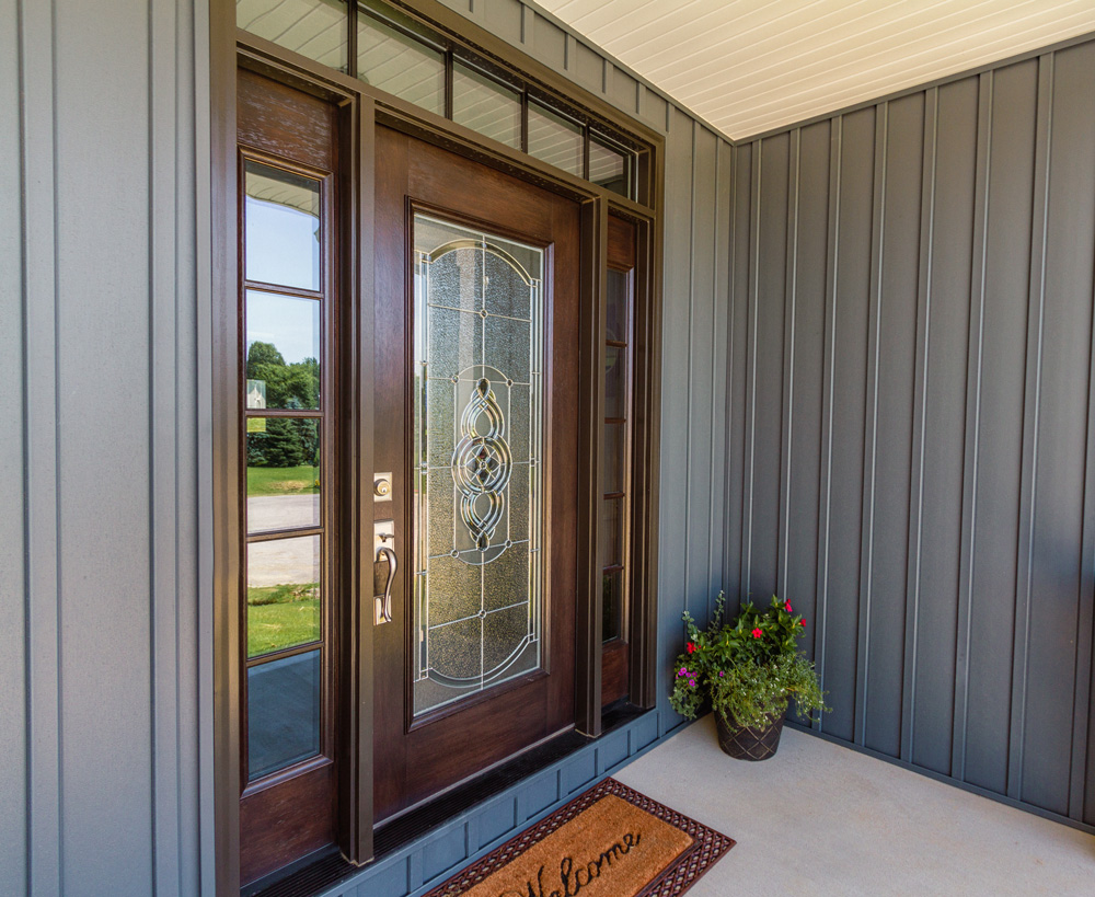 Showing Home design and ProVia Decorative Glass Entry Door with brown welcome mat and flower pot holding pink flowers by door.